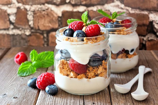 Blueberry raspberry parfaits mason jars side view rustic brick background