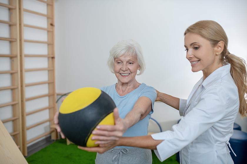 grey haired woman exercising with a ball