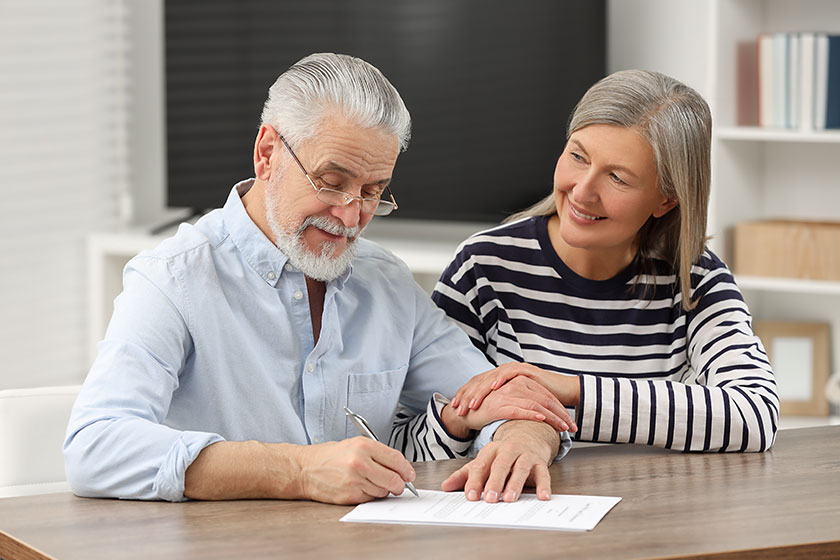 Happy senior couple signing last testament indoors Happy senior couple signing last testament indoors