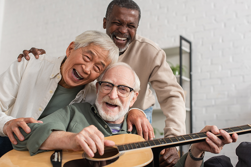 happy senior interracial friends playing acoustic guitar happy senior interracial friends playing acoustic guitar
