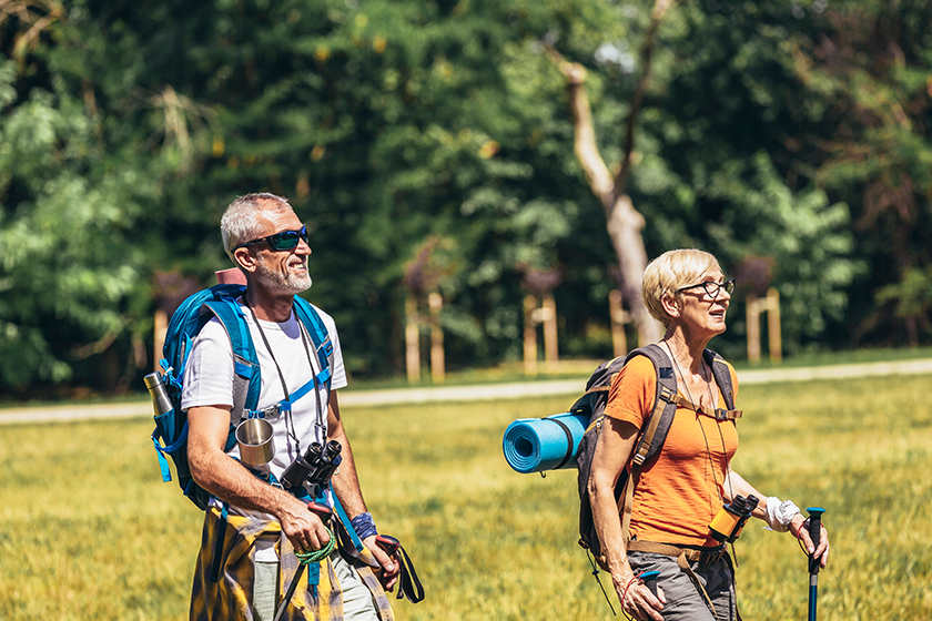 senior couple hiking forest wearing backpacks hiking