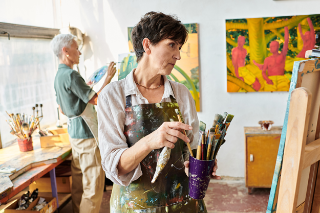thoughtful mature woman set paintbrushes female friend art workshop