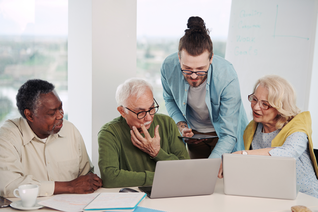 young hipster teacher explaining small group senior students laptops technology