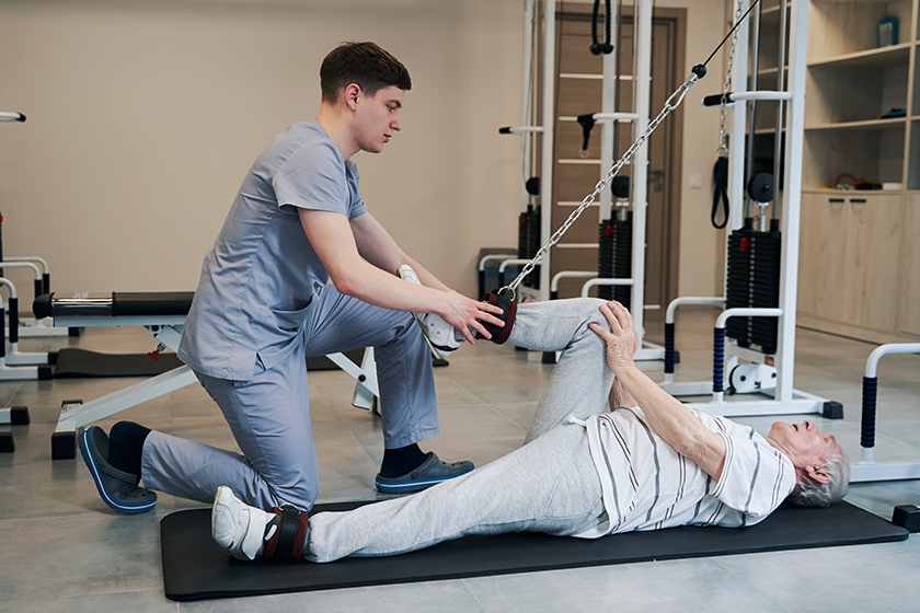 retired man bending knee with attached rope retired man bending knee with attached rope