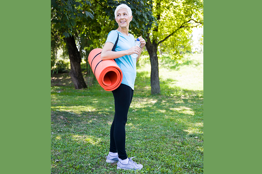 senior woman holds fitness mat