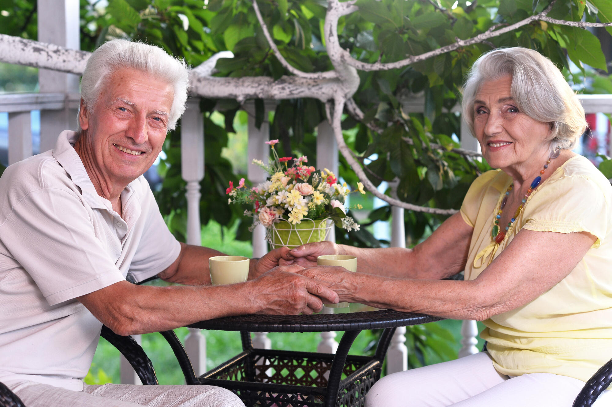 Elderly couple sitting at the table in the summer at the country house Elderly couple sitting at the table in the summer at the country house