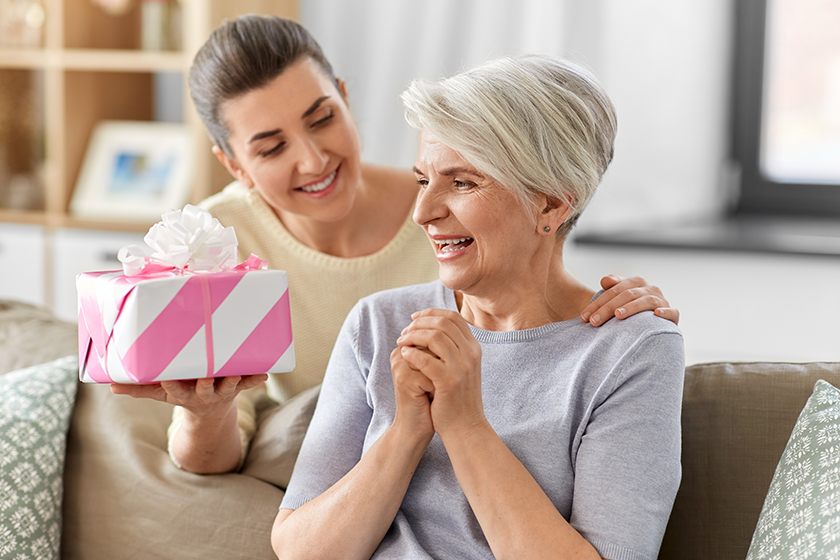adult daughter giving present to her senior mother
