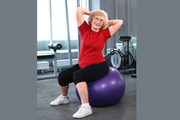 an elderly woman is engaged with a fitness ball