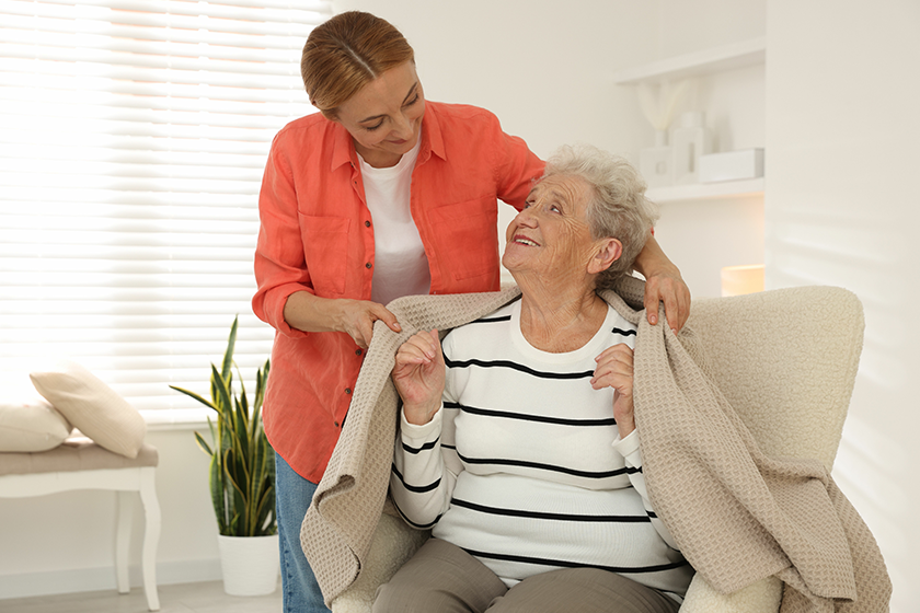 caregiver covering senior woman with blanket
