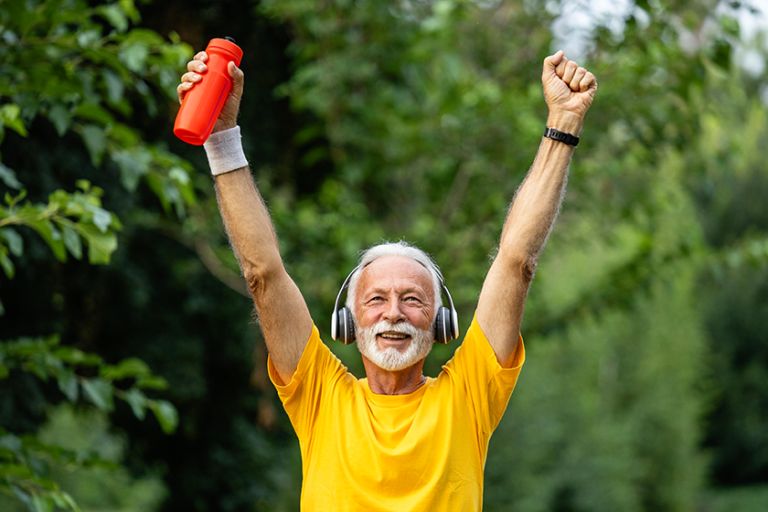 senior man arms raised crossing finish line