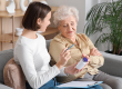young nurse giving pills senior woman sofa