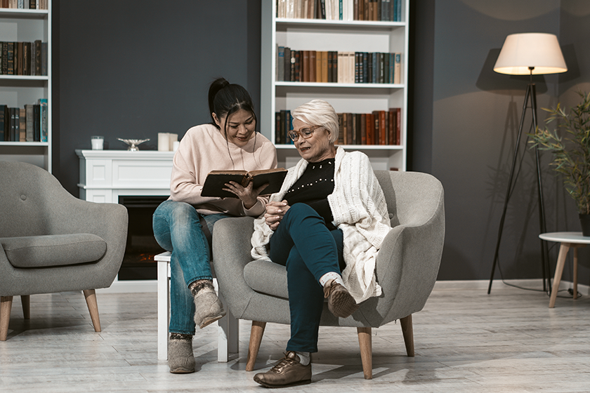 young woman reads book for her elderly mother